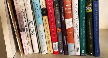 Rectangular photo of a closeup of books on a shelf, spanning titles on dogs and pets. Photo by Beth Miller.
