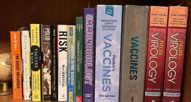 Rectangular photo of Charlotte Moser’s office bookshelf showing books on vaccines, virology, polio, smallpox, risks, and science communication. Photo credit: Charlotte Moser