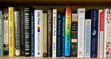 Rectangular photo of Lynne Peeples’ office bookshelf with titles on body clocks, sleep, and circadian science. Photo credit Lynne Peeples.