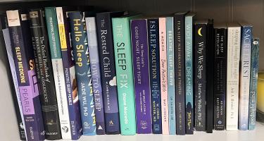 Rectangular photo of Funke Afolabi-Brown’s office bookshelf showing both academic and popular press books on sleep. Photo credit: Funke Afolabi-Brown