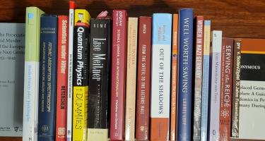 Rectangular photo of Olivia Campbell’s office bookshelf showing works on women in Nazi Germany, scientists under Hitler, displaced scholars in Nazi Germany in the 1930s, and physics. Photo credit: Olivia Campbell.