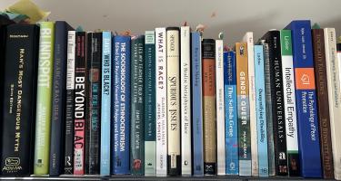 Rectangular photo of Carlos Hoyt’s office bookshelf showing books on race, sociology, gender, disability, blind spots, empathy, and other topics, along with a copy of Sneetches by Dr. Seuss. Photo credit: Carlos Hoyt.