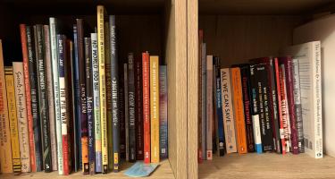 Rectangular photo of Jessica Fries-Gaither’s office bookshelf showing works on evolution, fossils, insects, weather, and other sciences, along with education and writing. Photo credit: Jessica Fries-Gaither.