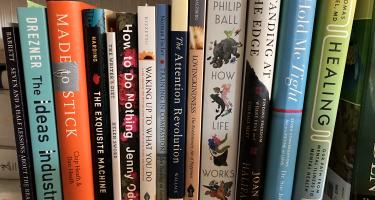 Rectangular photo of Ann Parson’s office bookshelf showing works on the brain, body, healing, love, and writing. Photo credit: Mary-Frances O’Connor.