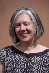 Studio portrait photo of Katie Mast smiling and wearing a boat neck top