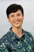 Portrait photo of Ari Remmel smiling and wearing a collared shirt with a botanical print motif