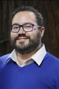 Portrait photo of Rodrigo Pérez Ortega wearing a sweater over collared shirt, glasses, and beard, smiling. Photo credit Lisa Strong.