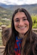 Portrait photo of Amanda Heidt smiling and posting in front of greenery and a mountain horizon