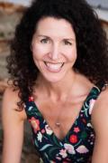 Portrait photo of Marla Broadfoot smiling, wearing a top with floral print